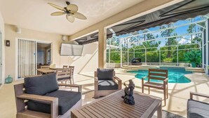 An outdoor seating area with a pool, a ceiling fan, and a TV. - Pool & Spa Oasis/Golf Retreat/Near Disney/3BR Home (davenport)