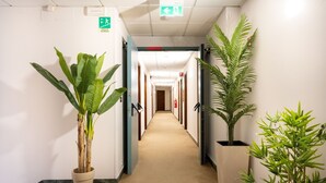 A hallway with potted plants, a fire alarm, and emergency exit signs. - CAMELIA ROOMS VENICE GUESTHOUSE (Mestre)