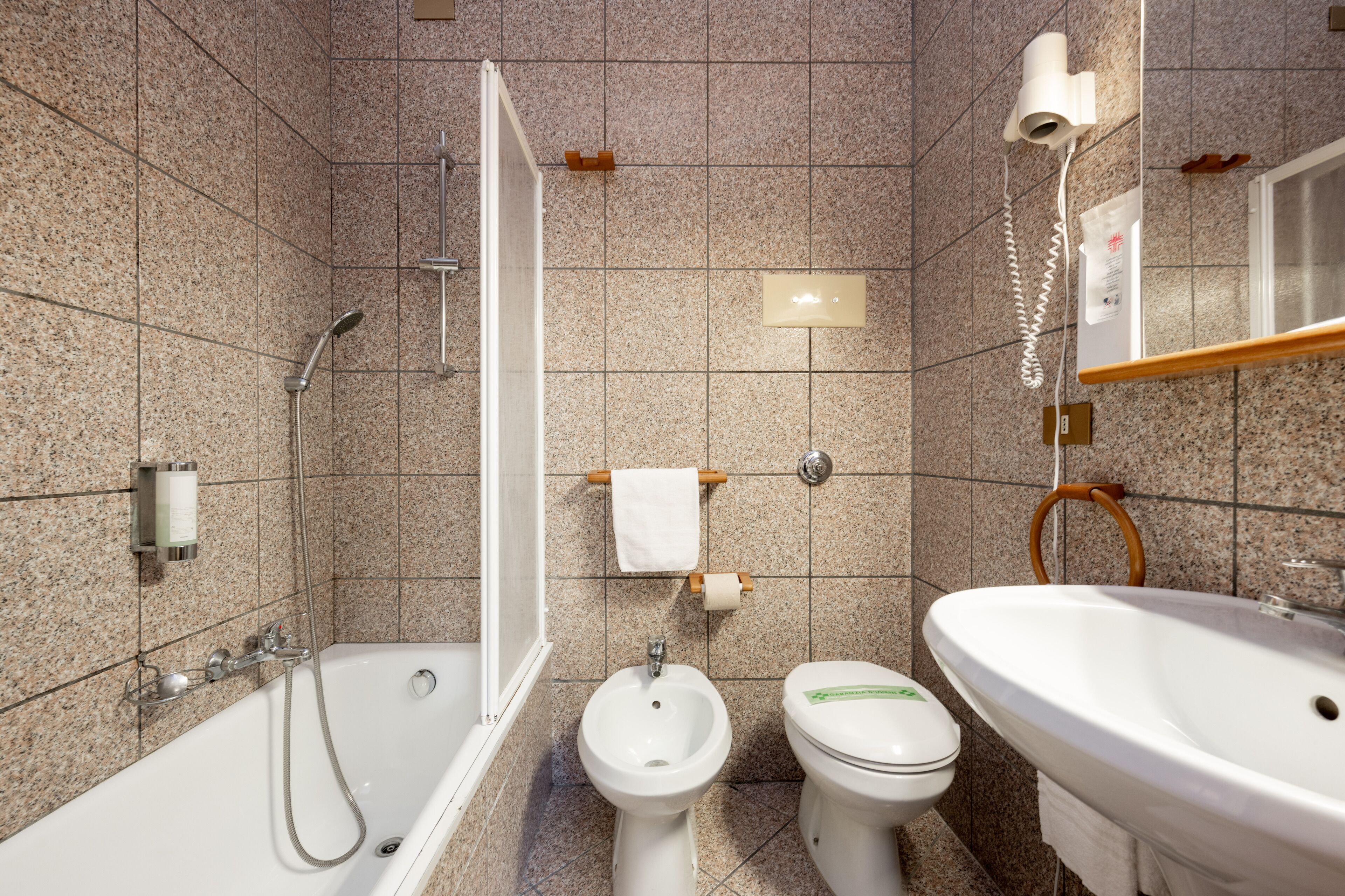 A bathroom with a bathtub, bidet, toilet, and sink.