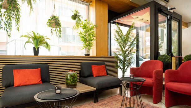 A modern lounge area with a sofa, red chairs, and a small table. - CAMELIA ROOMS VENICE GUESTHOUSE (Mestre)