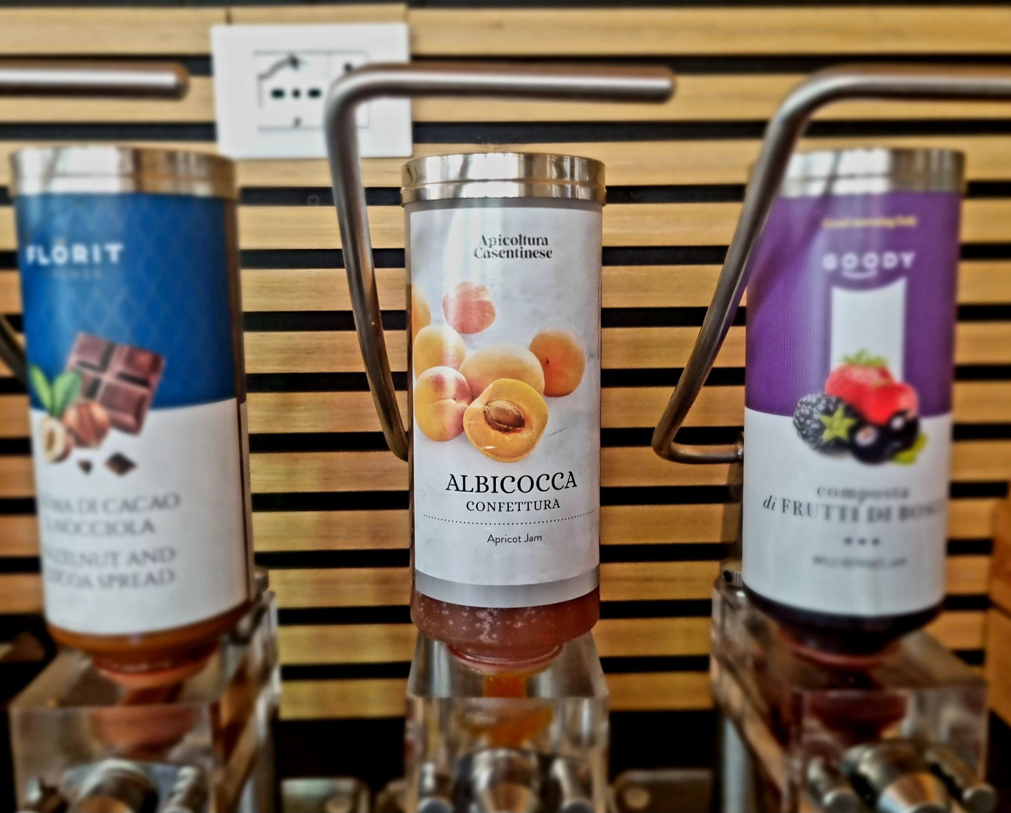 Three condiment dispensers with labels for different spreads.
