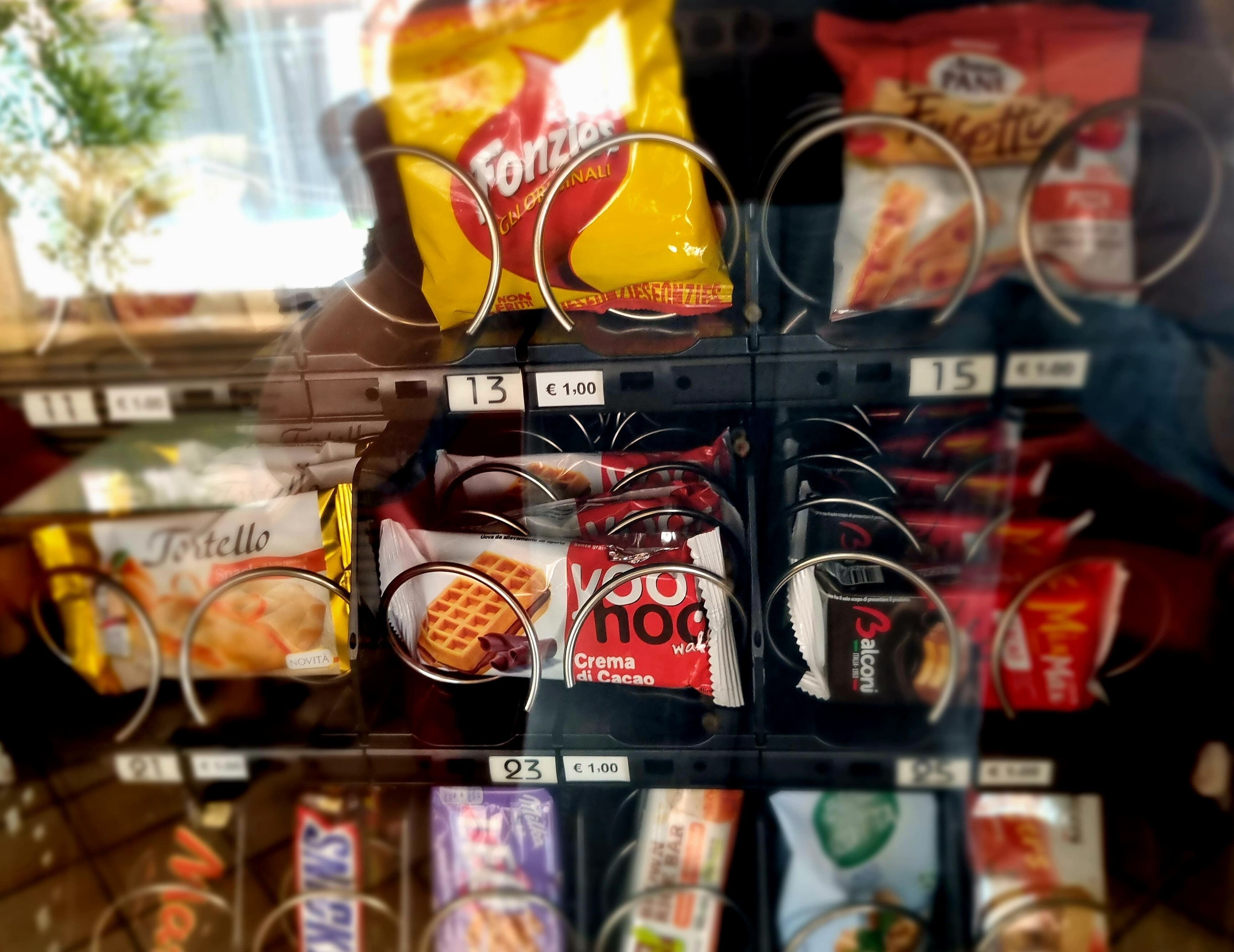Un assortiment d’en-cas et de desserts emballés, présentés sur une étagère dans un magasin, avec les étiquettes indiquant les prix.