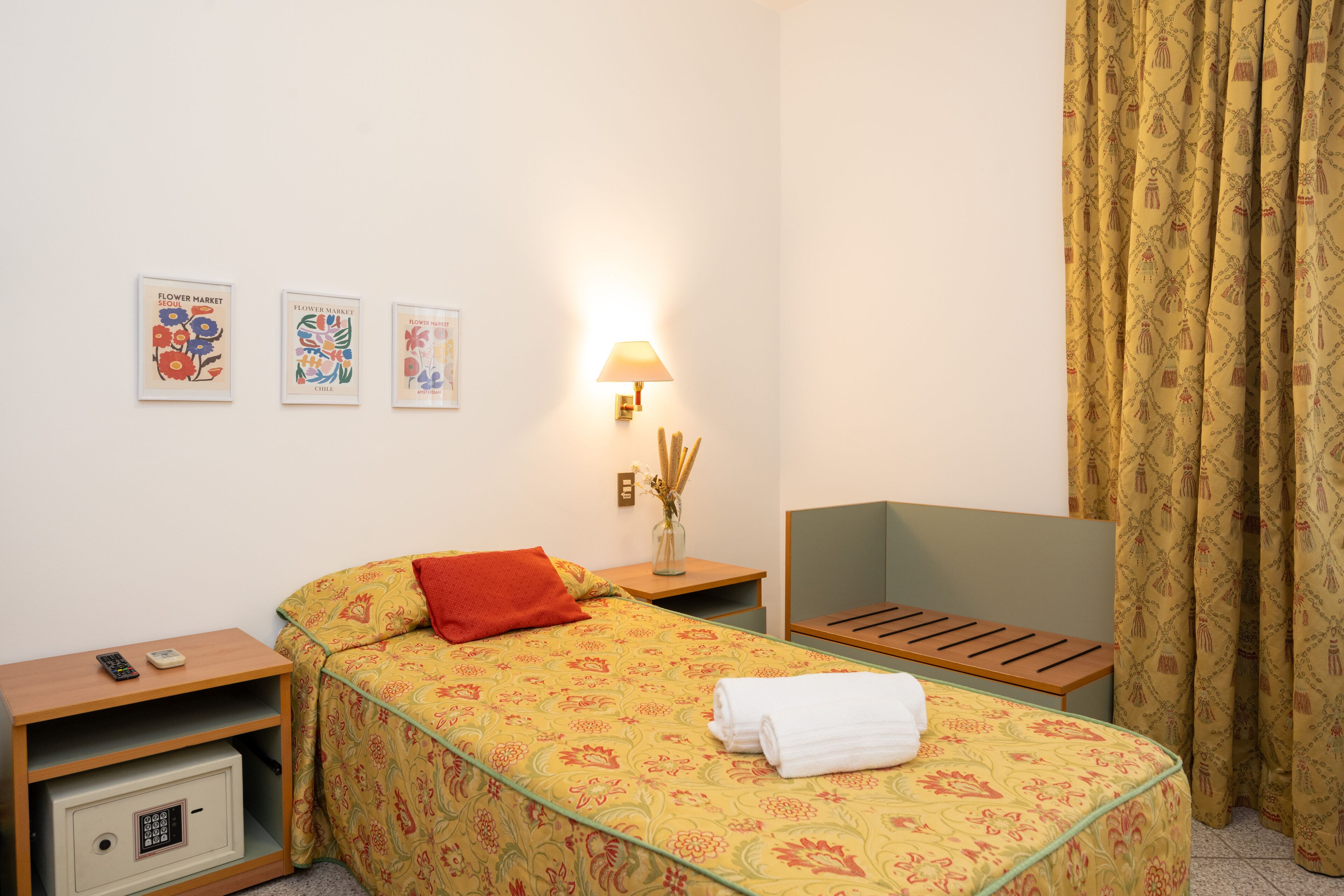 A hotel room with a bed, bedside tables, a lamp, and a small desk.