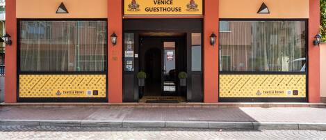 Entrada de um hotel com uma placa que diz "Venice Guesthouse" e "Camelia Rooms".