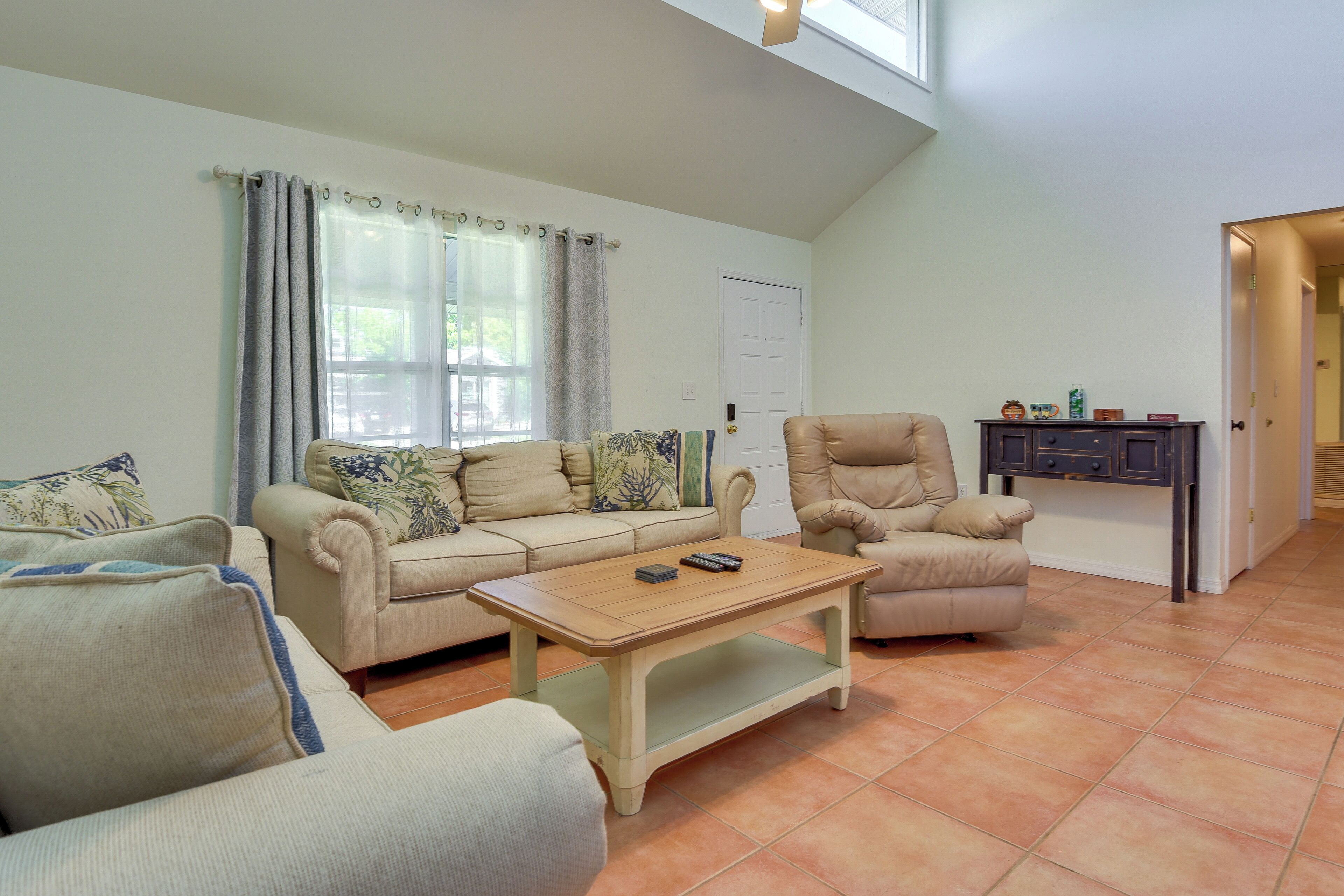 A living room with a beige sofa set, a wooden coffee table, and a leather armchair.