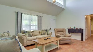 Un salón con un sofá beige, una mesa de centro de madera y un sillón de cuero.