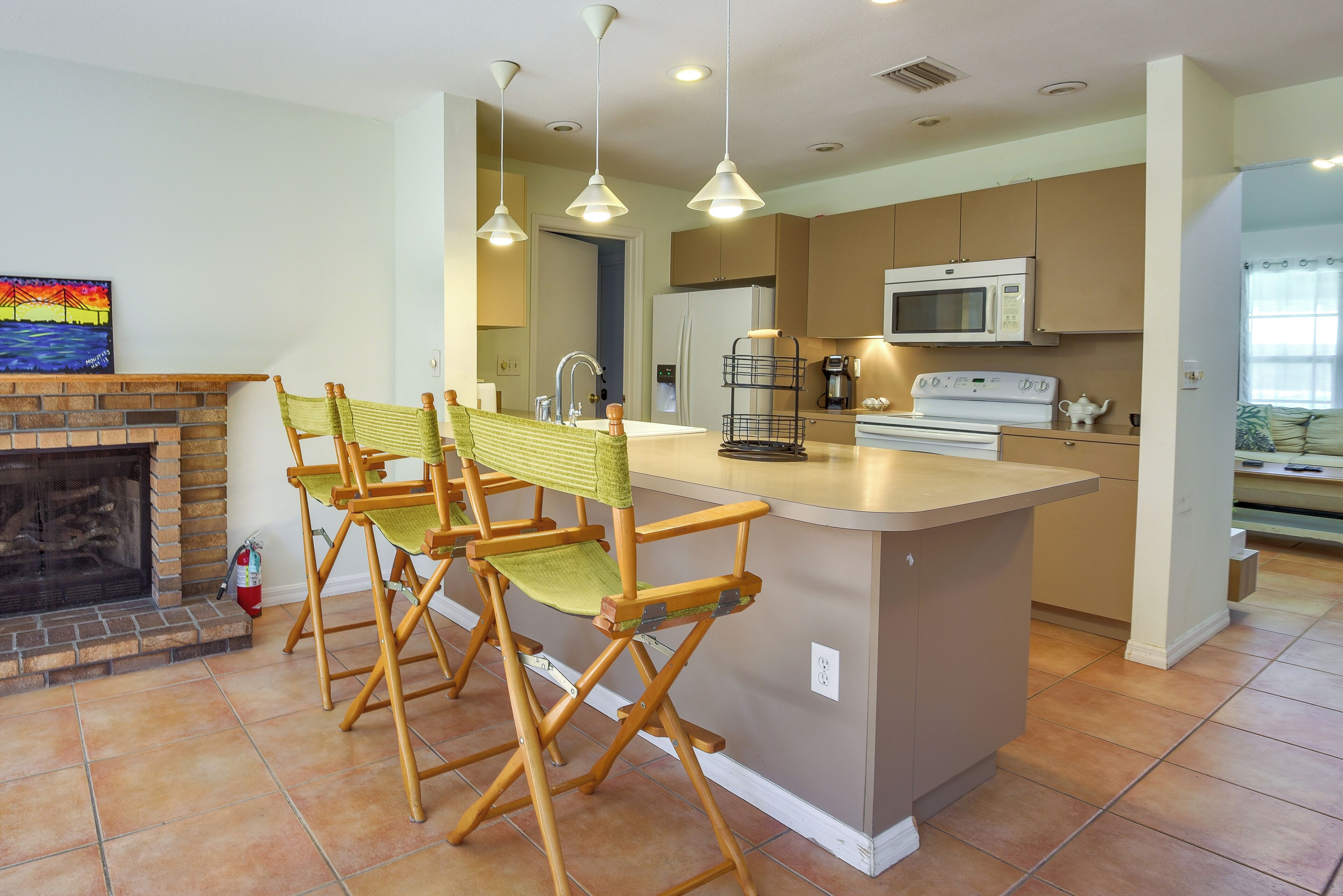 A modern kitchen with a central island, a built-in microwave, and a seating area with foldable chairs.