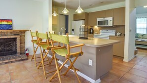 Una cocina moderna con una isla central, microondas integrado y una zona de estar con sillas plegables.