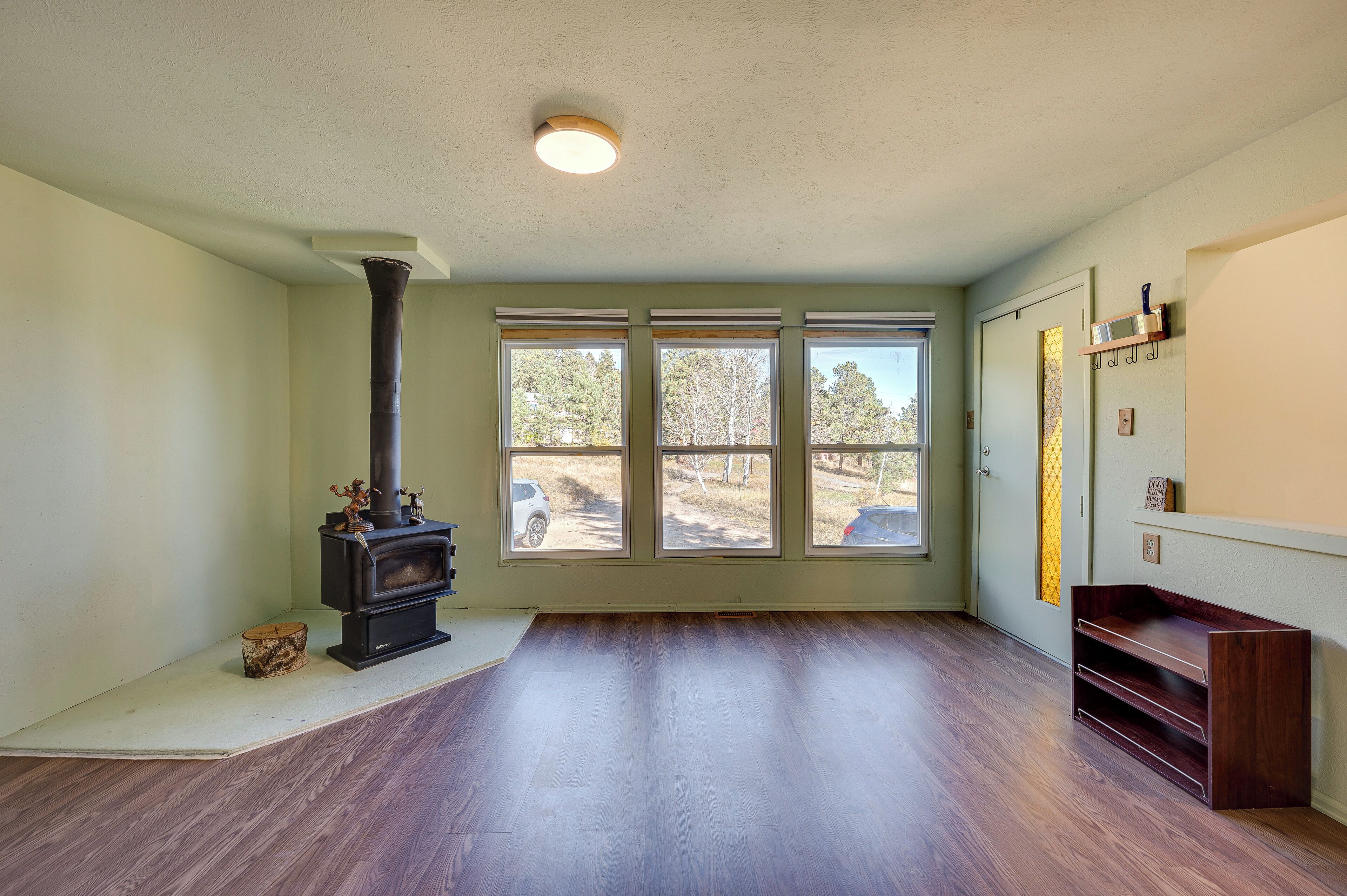 A room with a wood-burning stove, large windows, and a wooden bench.