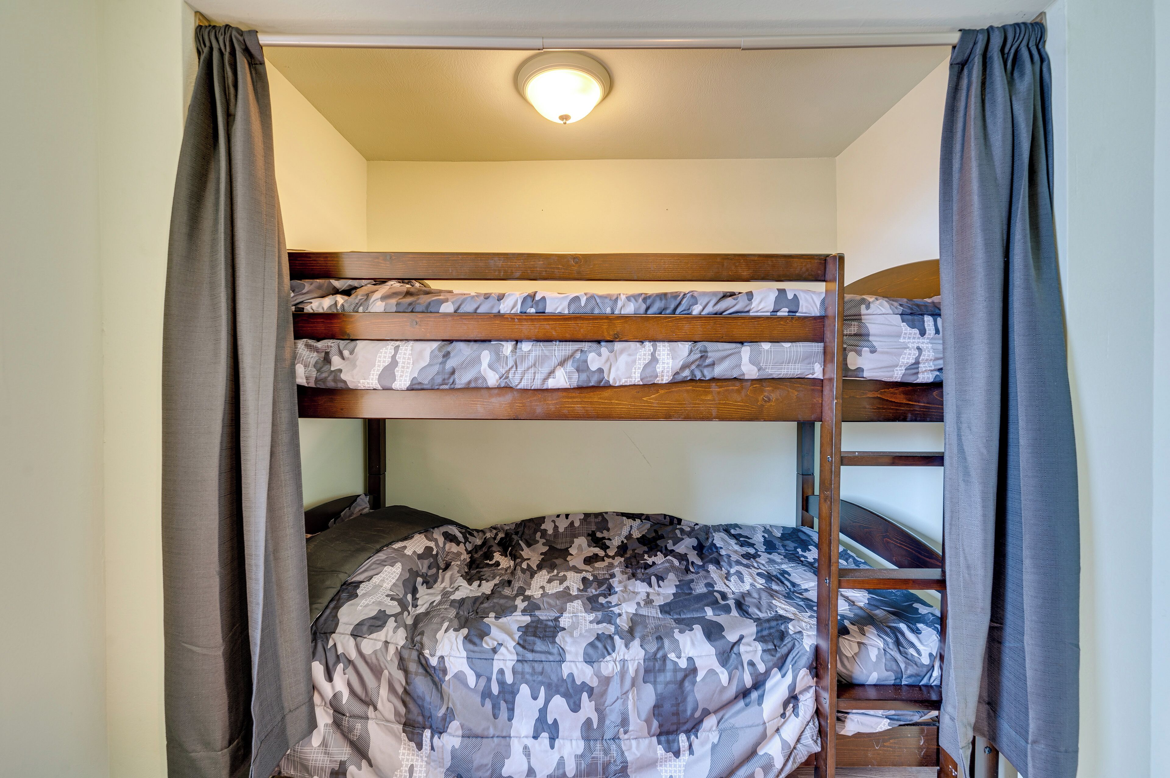 Una cama litera con ropa de cama y cortinas de camuflaje.