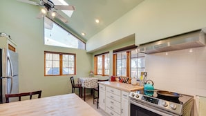 A kitchen with a wooden table, a stove, and a ceiling fan. - 17 Mi to Town: Peaceful Pet-friendly Golden Cabin! (Golden)