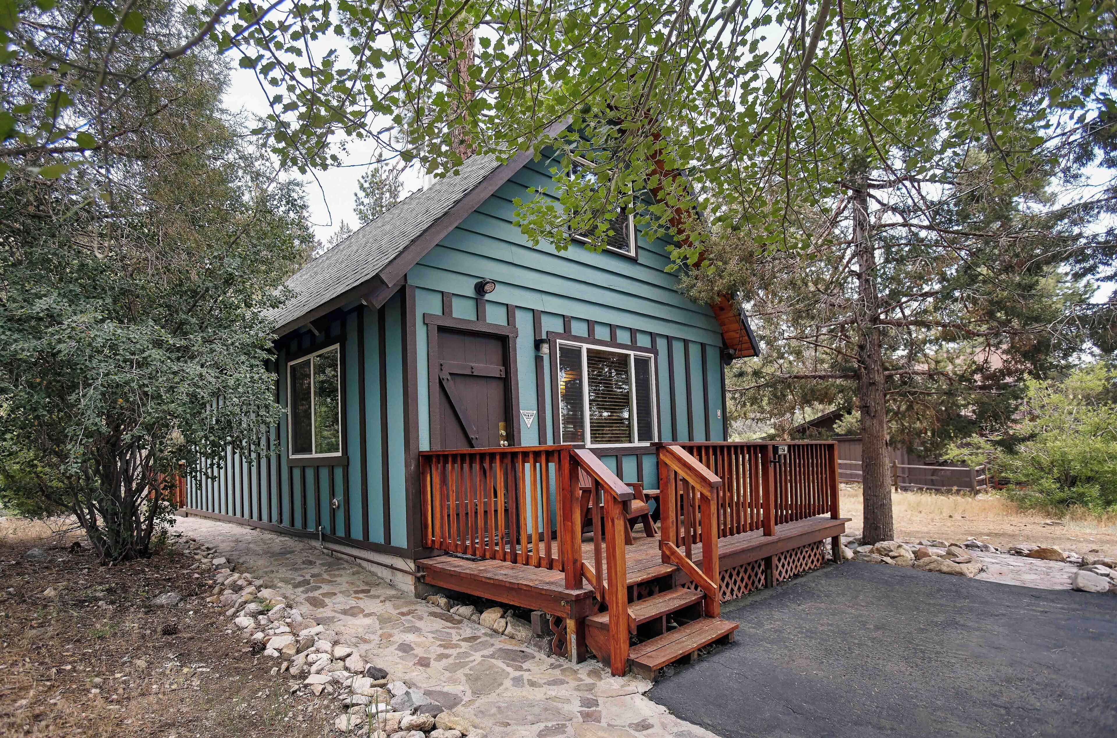 A small, single-story cabin with a wooden deck and steps leading to a front door.
