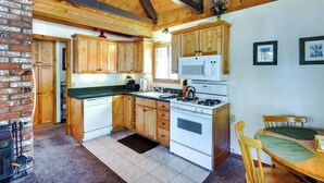A compact kitchen with wooden cabinets, a microwave, and a stove. - Hot Tub & Deck: Big Bear City Cabin Near Skiing (Big Bear City)