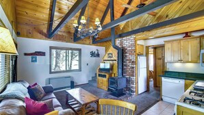 A cozy cabin interior with a living room, fireplace, kitchen, and wooden beams. - Hot Tub & Deck: Big Bear City Cabin Near Skiing (Big Bear City)