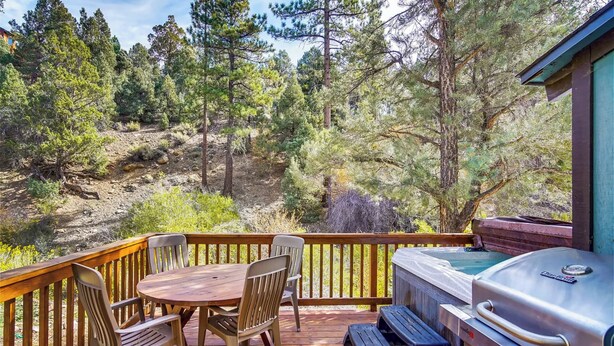 A deck with a wooden table and chairs, a grill, and a view of a forested area. - Hot Tub & Deck: Big Bear City Cabin Near Skiing (Big Bear City)