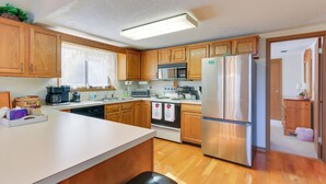 Una cocina con armarios de madera, un refrigerador de acero inoxidable, un microondas y una estufa.