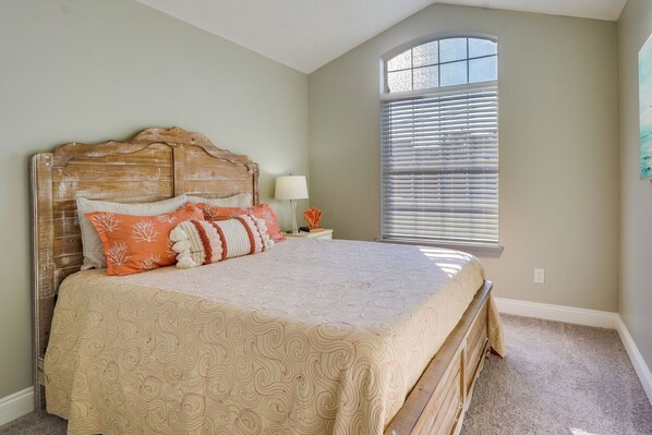 Un dormitorio con cama, mesita de noche, lámpara y ventana con persianas.