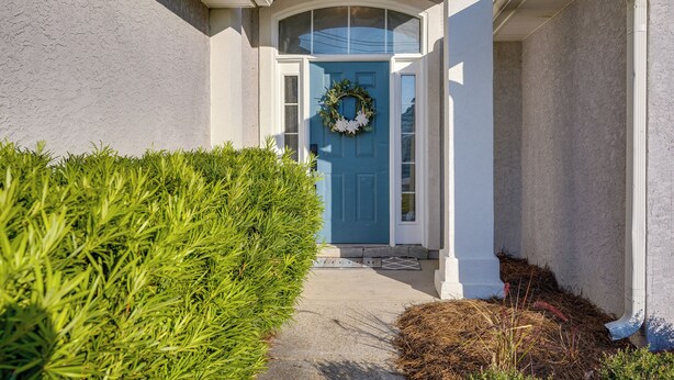 A house with a blue front door, a wreath, and a well-maintained hedge. - Family-friendly PCB Vacation Rental, Walk to Beach (Panama City Beach)