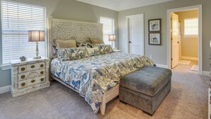 A bedroom with a bed, nightstands, a dresser, a ceiling fan, and a door leading to another room. - Family-friendly PCB Vacation Rental, Walk to Beach (Panama City Beach)
