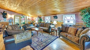 Un salon chaleureux avec un plafond en bois, des canapés en cuir, un tapis à motifs et divers objets de décoration.