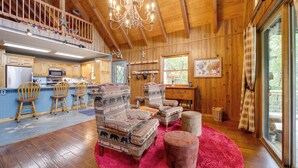 A spacious living room with wooden walls, a red rug, and a balcony with a star decoration. - Robbinsville Vacation Rental w/ Covered Balcony (Robbinsville)
