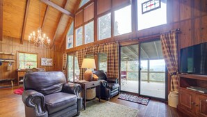 A cozy cabin interior with a leather sofa, a table with a lamp, and a television on a wooden cabinet. - Robbinsville Vacation Rental w/ Covered Balcony (Robbinsville)