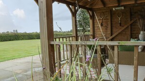 A wooden gazebo with a view of a grassy field.