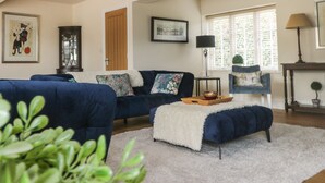 A living room with a blue sofa set, a white fluffy rug, and a wooden coffee table.