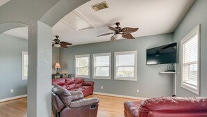 A spacious living room with a ceiling fan, a flat-screen TV, and a leather sofa. - Waterfront Sargent Home w/ Kayaks & Boat Dock! (Bay City)