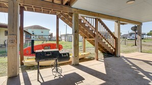 A covered outdoor area with a wooden staircase, a barbecue grill, and boats. - Waterfront Sargent Home w/ Kayaks & Boat Dock! (Bay City)