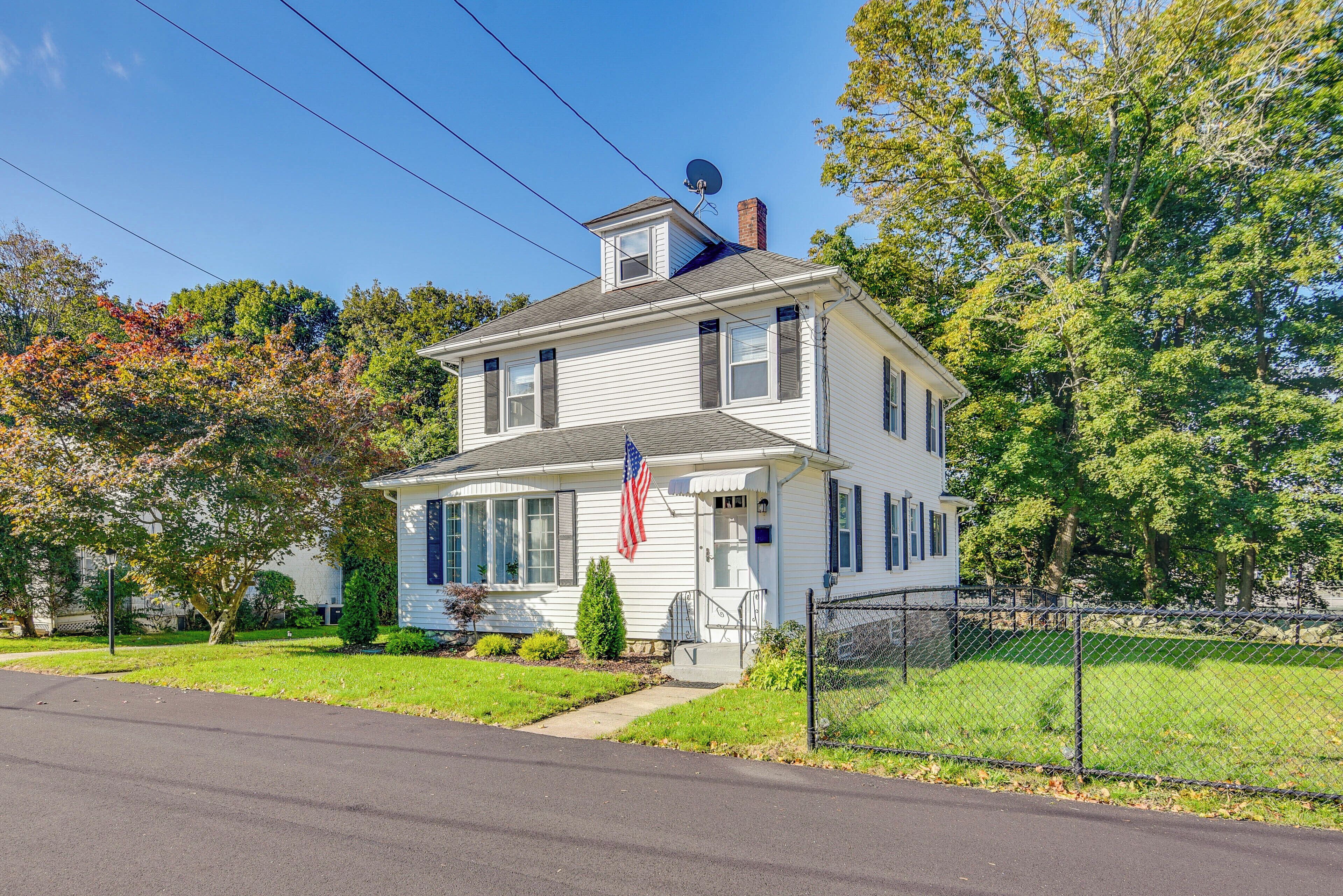 A two-story house with a front porch, a satellite dish, and an American flag.