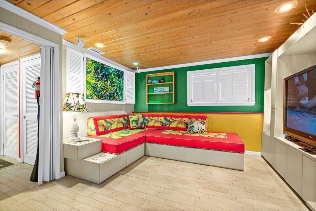 A cozy living room with a sectional sofa, a television, and a green accent wall.