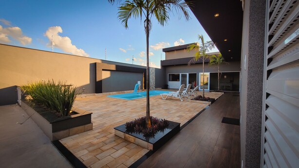 Un espace piscine extérieur moderne, avec un ciel dégagé, un palmier et un fauteuil de relaxation.