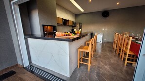 Une cuisine moderne dotée d’un plan de travail en marbre, de tabourets de bar en bois et d’un coin repas avec des chaises en bois et une nappe rouge.