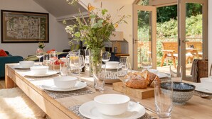 Une table à manger dressée avec de l’assiette blanche, des bols, des verres et un vase rempli de fleurs.