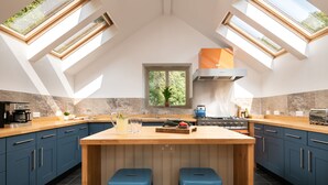 Une cuisine moderne dotée d’un îlot central, de lucarnes et d’armoires bleu foncé.