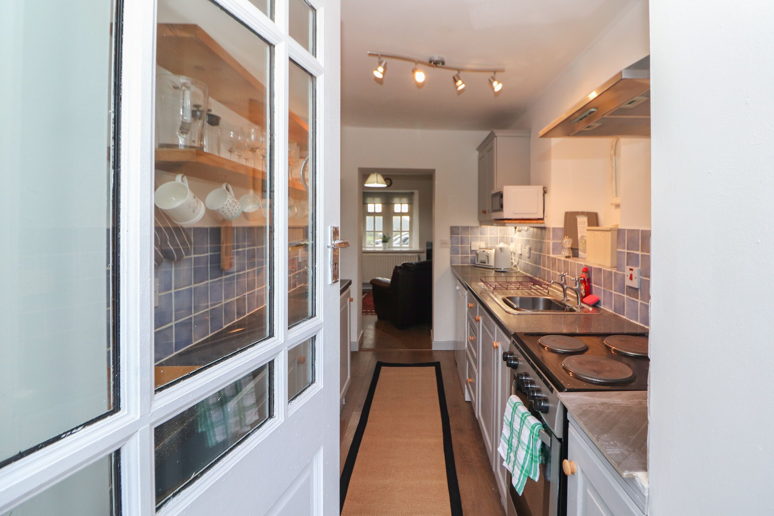 A kitchen with a stove, sink, and cabinets. There is a window with a view of the outside.