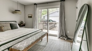 A bedroom with a bed, a ceiling fan, a window with curtains, and a view of the outside.