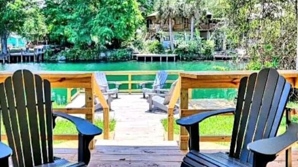 A wooden deck with two Adirondack chairs facing a pool. - Weeki Wachee Waterfront-A Frame Stream Dream Cabin (Spring Hill)
