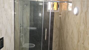 A modern bathroom with a glass-enclosed shower, a toilet, and a sink.