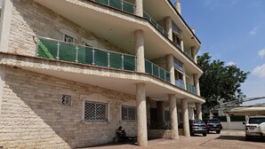A multi-story building with a stone facade, balconies, and a covered entrance area. - Kams homes (Abuja)