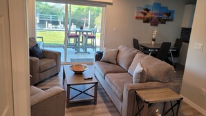 A living room with a sofa, armchairs, a coffee table, and a dining area with a table and chairs.