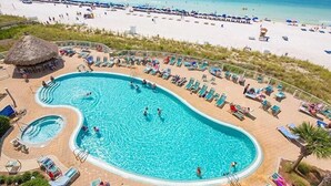 A large pool surrounded by sun loungers and a beach view.