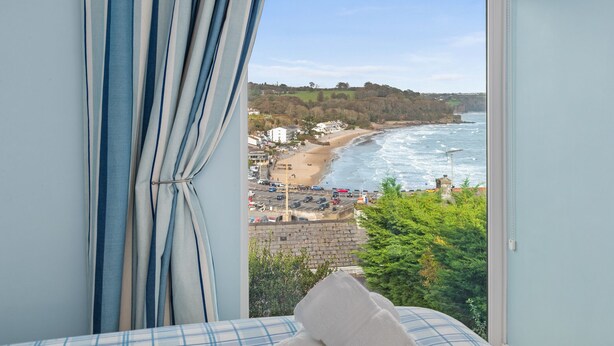 A room with a large window overlooking a beach and ocean.