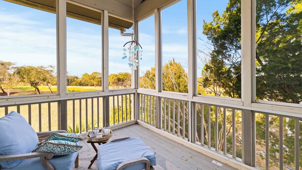 A covered outdoor deck with a bed, pillows, and a small table. - Linkside Court 21 - Community Tennis/Pickleball! (Isle of Palms)