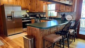 Una cocina con armarios de madera, electrodomésticos de acero inoxidable, una isla grande con taburetes de bar y un cartel de bienvenida.