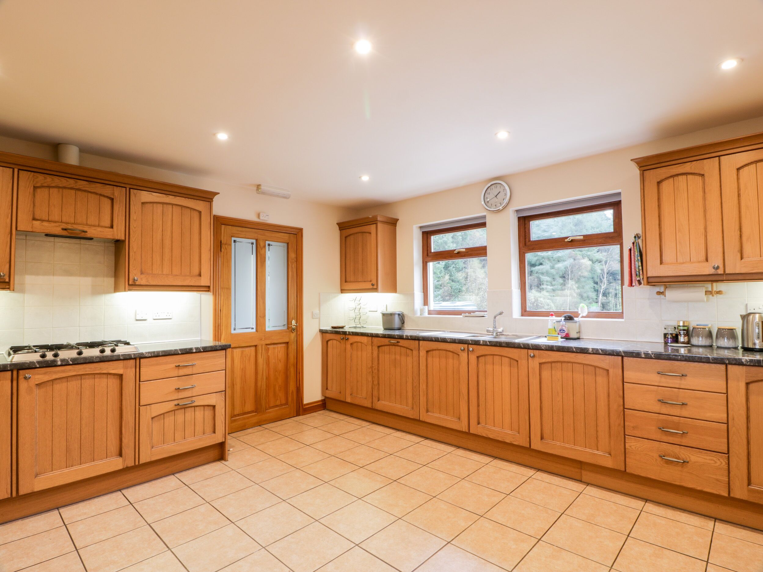 A spacious kitchen with wooden cabinets, a gas stove, a sink, and a window providing natural light.