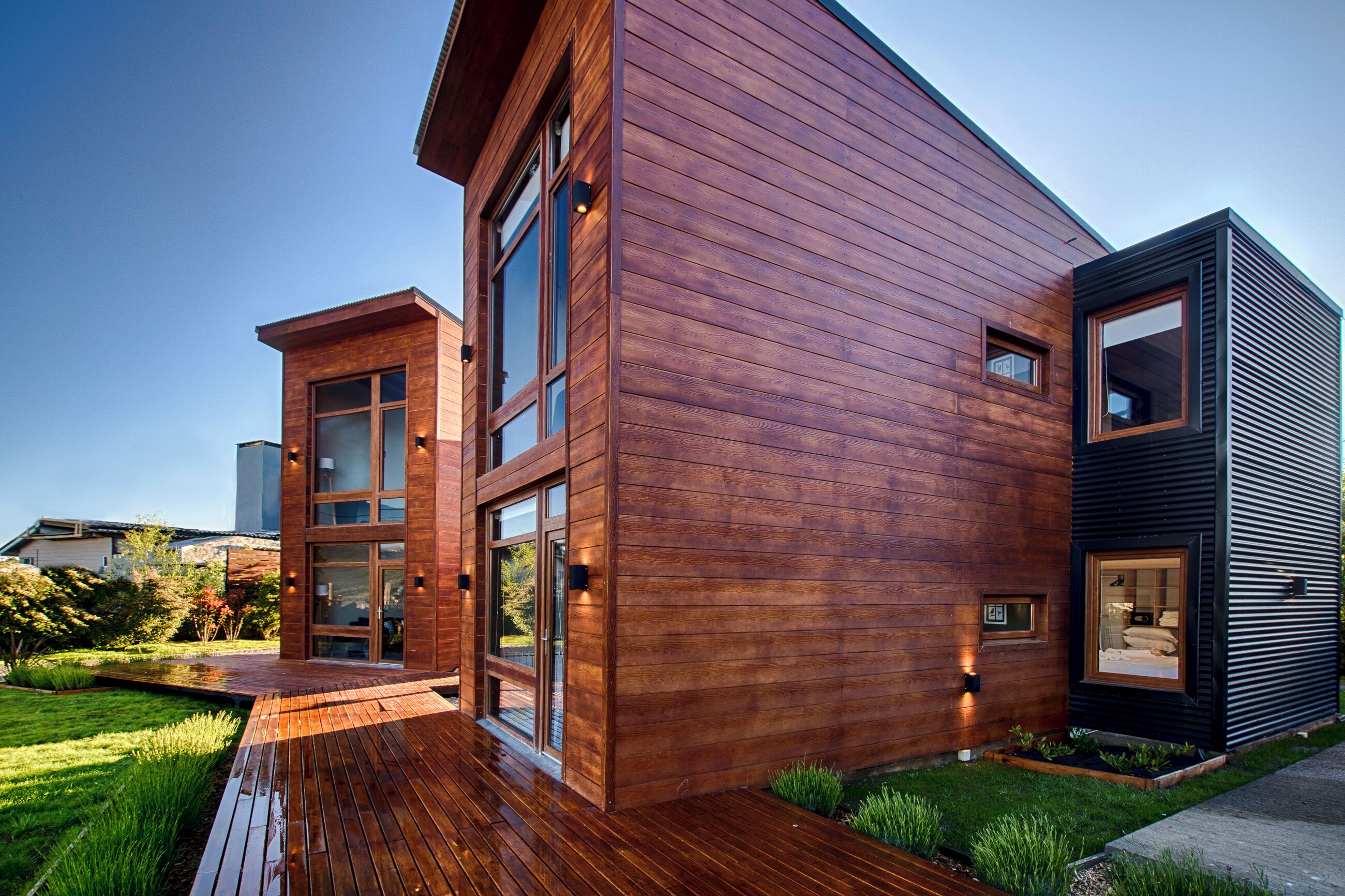 A modern two-story building with a wooden facade, large windows, and a wooden deck.