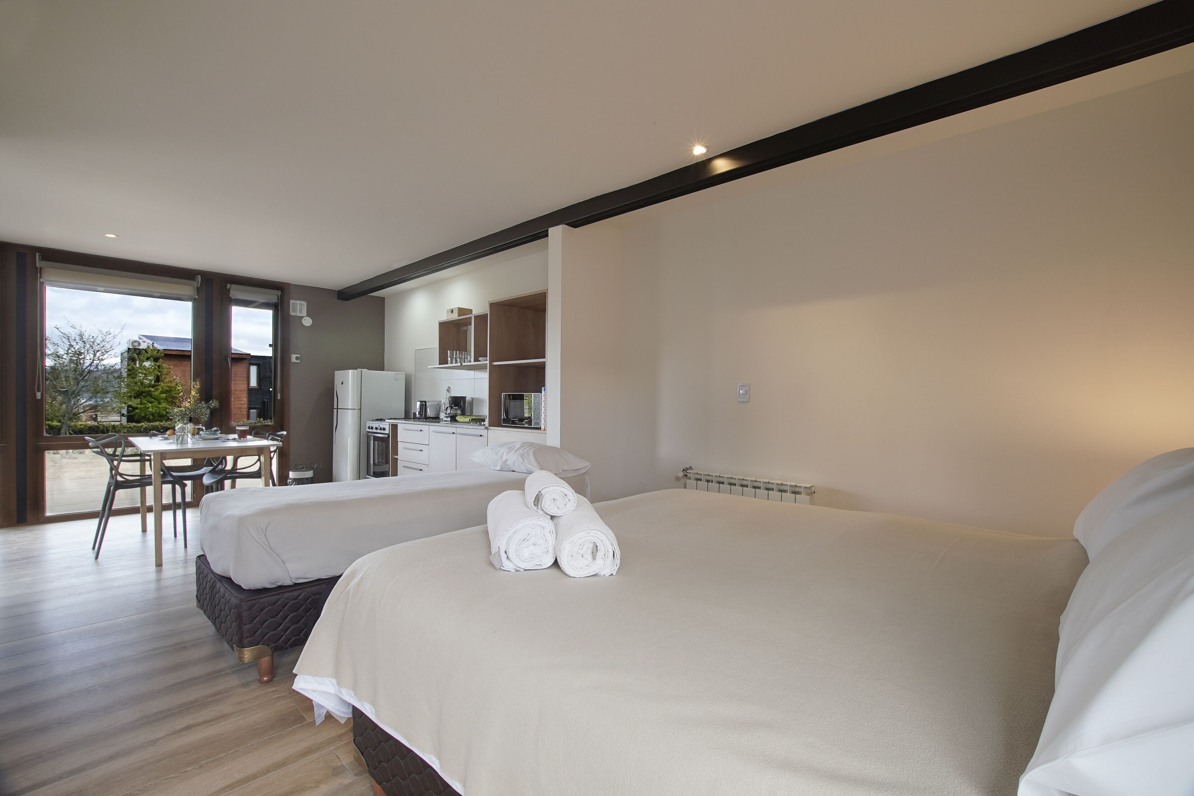 Una habitación de hotel moderna con dos camas, un comedor y una kitchenette.