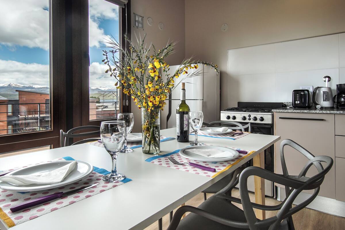Una mesa de comedor dispuesta con platos, vasos y un florero.